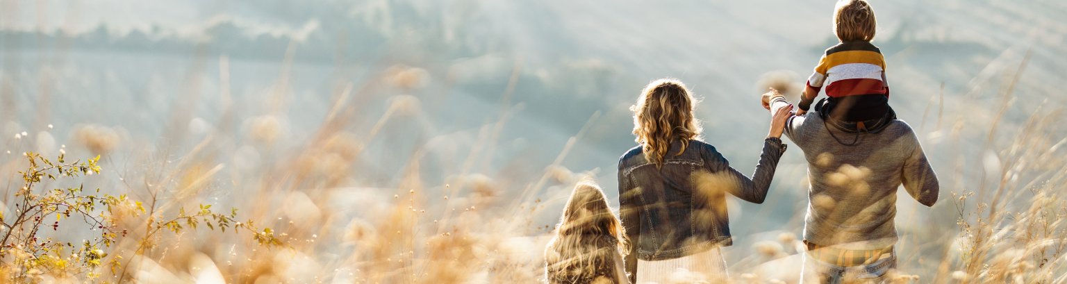 Rear view of a family standing on a hill in autumn day.